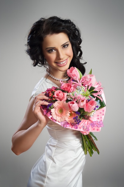 schönes Mädchen in einem weißen Hochzeitskleid mit einem Blumenstrauß