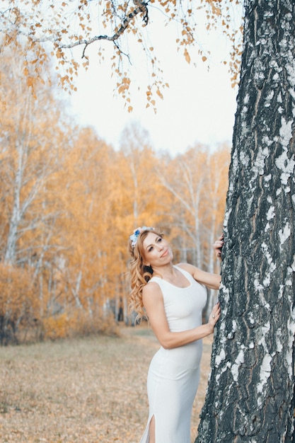 Schönes mädchen in einem weißen kleid im herbstwald. naturspaziergang. energie von der sonne bekommen, bäume. märchenszene einer frau, die im wald liegt