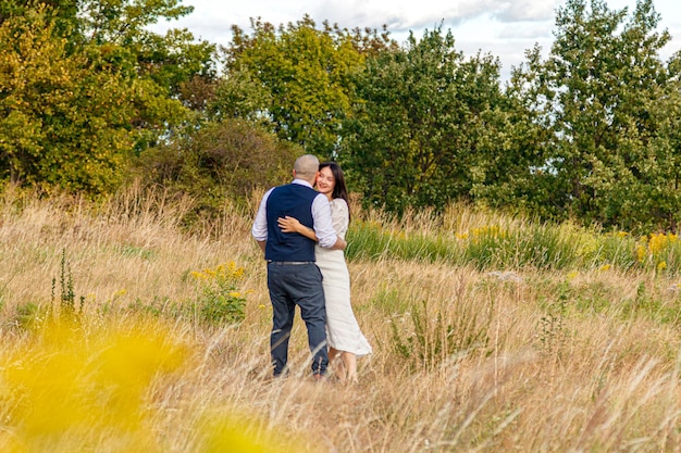 schönes Mädchen in einem weißen Kleid und ein Mann auf einem Feld vor einem blauen Himmel mit Wolken in Nahaufnahme