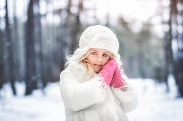 Foto schönes mädchen in einem weißen mantel im wald im winter