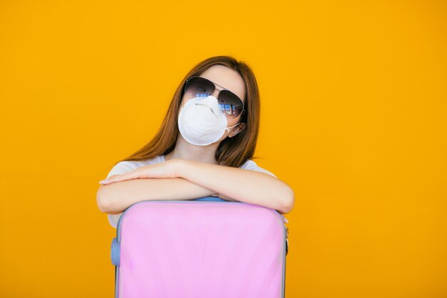 Schönes Mädchen in einem weißen Sommerkleid mit einem Koffer Medizinische Maske im Gesicht Geschlossene Grenzen