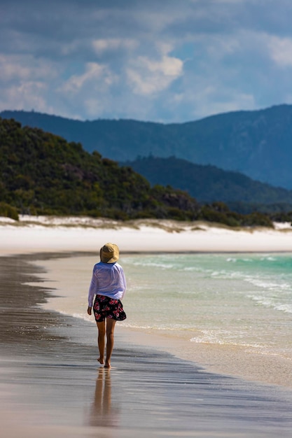 schönes mädchen in kleid und hemd und hut geht am whitehaven beach, whitsunday island, australien