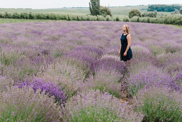 Schönes Mädchen in lila Lavendelfeld Schöne Frau zu Fuß auf dem Lavendelfeld Genießen Sie die florale Lichtung Sommernatur Naturkosmetik und Öko-Make-up-Konzept