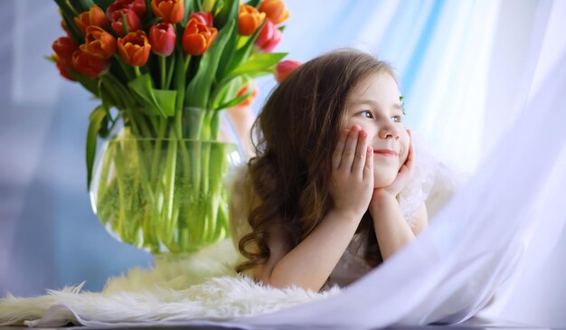 Schönes Mädchen in weißen Kleidern mit einem prächtigen Strauß der ersten Tulpen Internationaler Frauentag Mädchen mit Tulpen