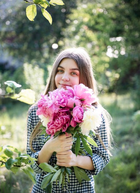 Schönes Mädchen mit Blumenstrauß von Pfingstrosen