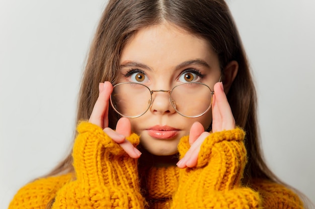 Schönes Mädchen mit Brille und gelbem Pullover auf weißem Hintergrund