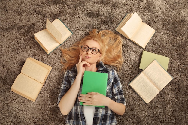 Foto schönes mädchen mit büchern, die auf dem boden liegen