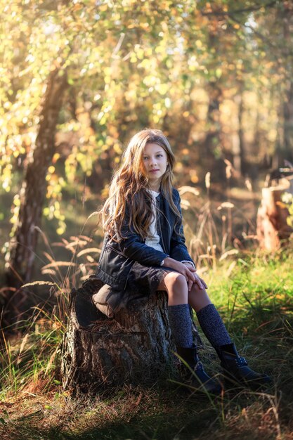 schönes Mädchen mit dem langen Haar, das auf Natur sitzt