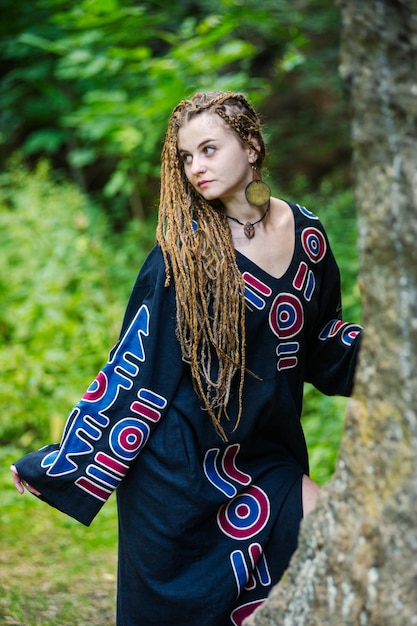 Schönes Mädchen mit Dreadlocks im Hippie-Stil posiert im Freien