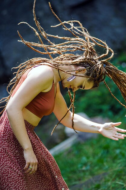 Schönes Mädchen mit Dreadlocks im Hippie-Stil posiert im Freien