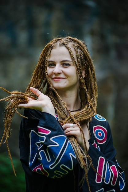 Schönes Mädchen mit Dreadlocks im Hippie-Stil posiert im Freien