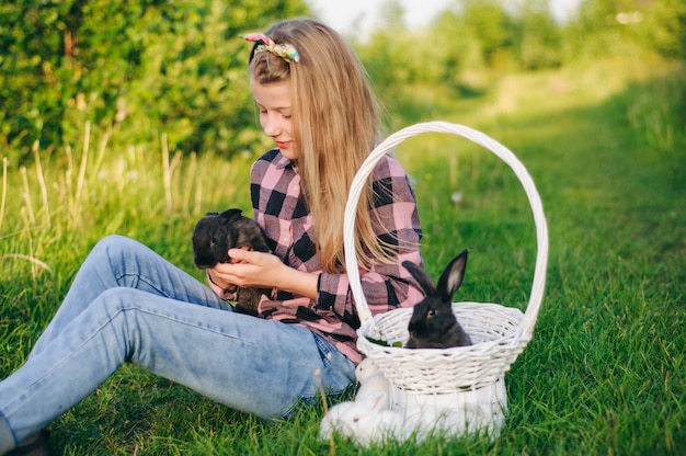 schönes Mädchen mit einem Kaninchen. Mädchen lacht und küsst ein Kaninchen. Kartenhemd und Jeans. Osterhase. laut auflachen