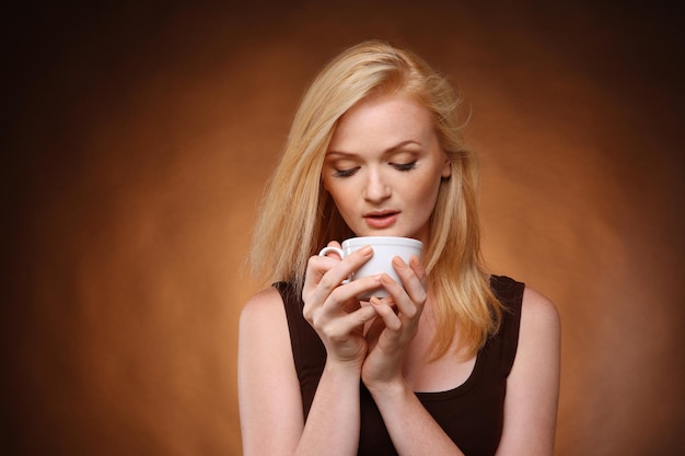 Schönes Mädchen mit einer Tasse Kaffee auf dunklem Hintergrund