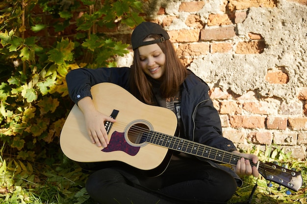 Schönes Mädchen mit Gitarre im Freien