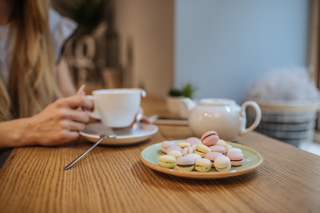 Schönes Mädchen mit heißem Getränk, das in einem Café entspannt