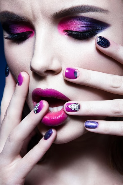 Schönes Mädchen mit hellem, kreativem Mode-Make-up und buntem Nagellack Art Beauty Design