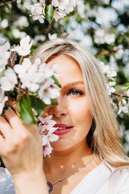 Schönes Mädchen mit hellen Haaren, Brille, in der Nähe von blühenden Bäumen, Apfelbaum, Frühling, Ästen, Blumen, Mode, Stil, europäisch, rot