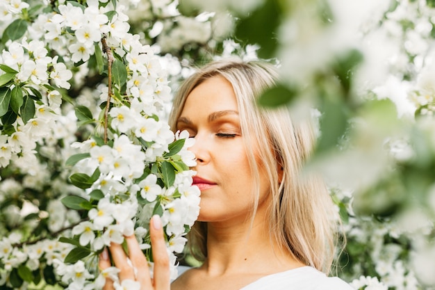 Schönes Mädchen mit hellen Haaren, Brille, in der Nähe von blühenden Bäumen, Apfelbaum, Frühling, Ästen, Blumen, Mode, Stil, europäisch, rot