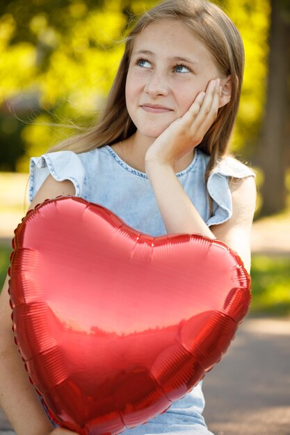 Schönes Mädchen mit herzförmigem Ballon