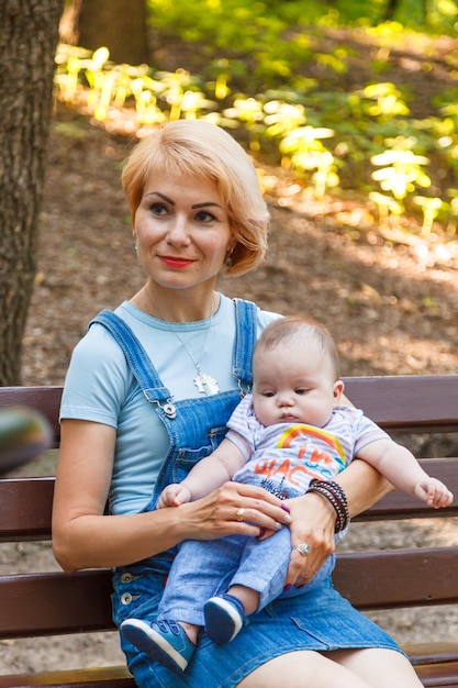 Schönes Mädchen mit Kindern sitzt auf einer Bank im Park