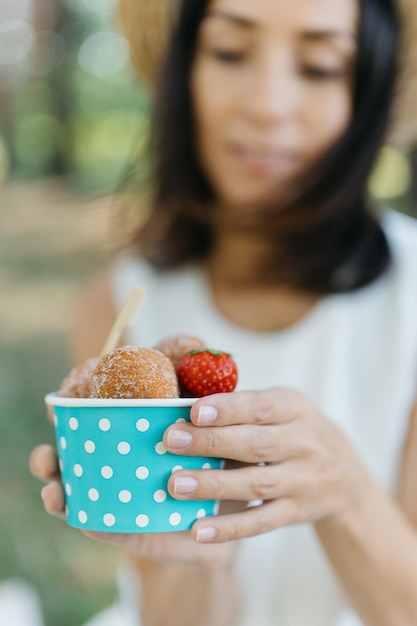 Schönes Mädchen mit kleinem Strohhut und weißem Anzug mit Käsebällchen oder Eis in der Hand