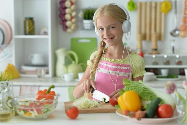 Schönes Mädchen mit Kopfhörern, das in der Küche kocht