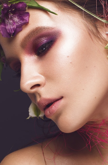 Schönes Mädchen mit Kunstmake-up und -blumen