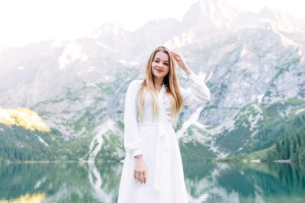 Foto schönes mädchen mit langen haaren in einem weißen kleid schaut in die kamera