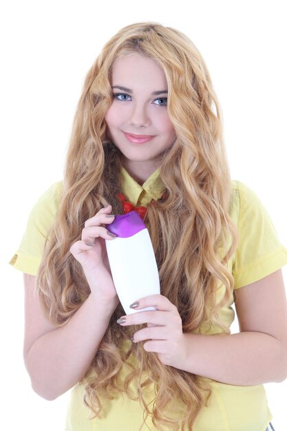 schönes Mädchen mit langen lockigen Haaren und einer Flasche Shampoo in der Hand