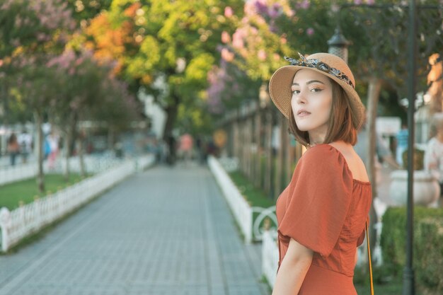 Schönes mädchen mit orangefarbenem kleid, das während des sonnenuntergangs von istanbul mit der hagia sophia posiert