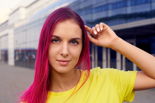 Schönes Mädchen mit rosa Haaren und einem gelben T-Shirt, horizontale Porträtnahaufnahme