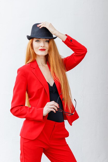 Schönes Mädchen mit roten Haaren, gekleidet in einem roten Business-Anzug Business-Porträt