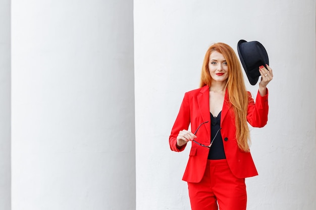 Schönes Mädchen mit roten Haaren, gekleidet in einem roten Business-Anzug Business-Porträt