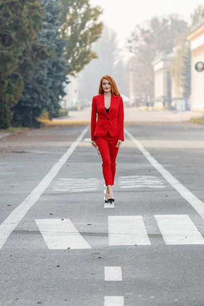 Schönes Mädchen mit roten Haaren, gekleidet in einem roten Business-Anzug Business-Porträt