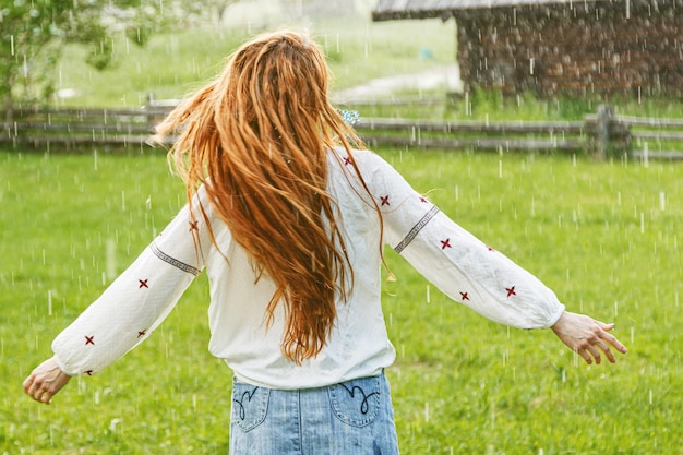 Foto schönes mädchen mit roten haaren in ukrainischer stickerei im regen gekleidet