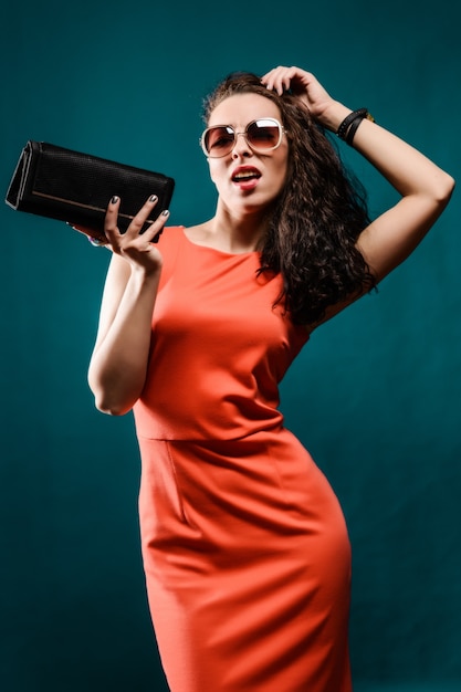 Schönes Mädchen mit Sonnenbrille und Handtasche in ihren Händen