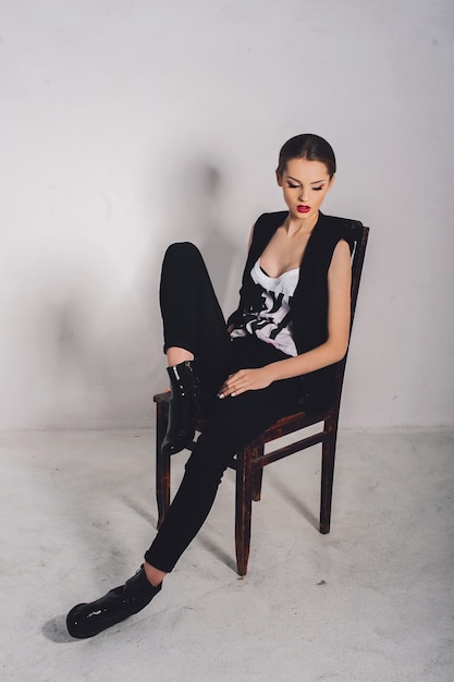 schönes Mädchen Modell sitzt auf einem Stuhl im Studio