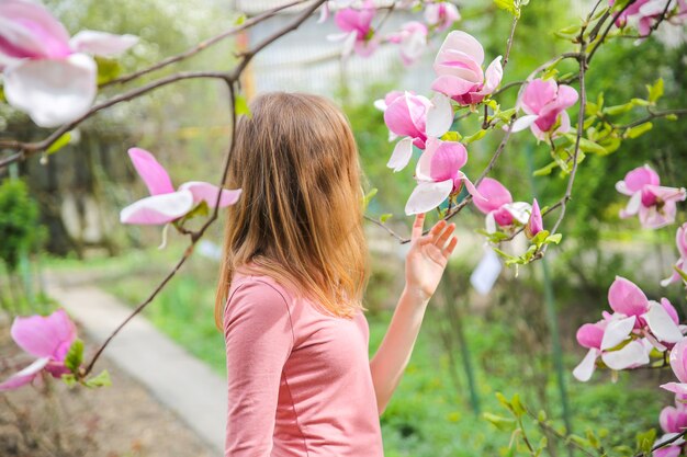 Schönes Mädchen nahe blühendem Baum. Blühen Sie Magnolie im Freien. Frühlingsstimmung. Frau entspannt.