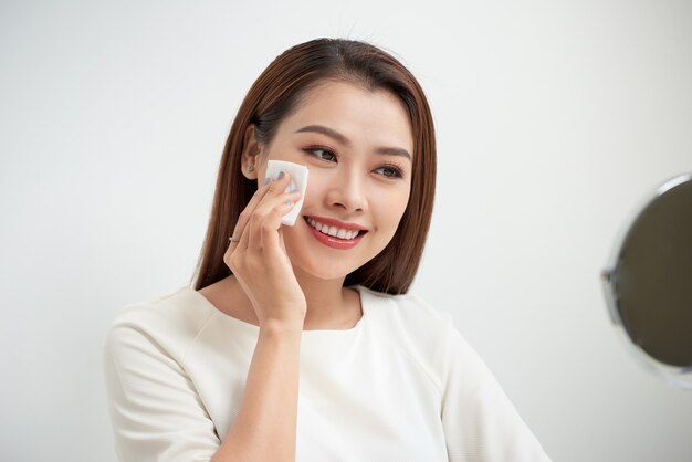 Schönes Mädchen reinigt das Gesicht von Make-up mit einem Wattepad