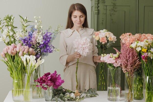 Schönes Mädchen sammelt einen Blumenstrauß in einem Blumenladen