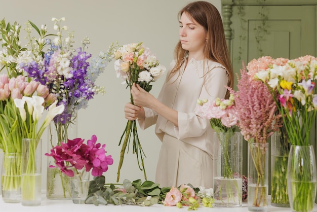 Schönes Mädchen sammelt einen Blumenstrauß in einem Blumenladen