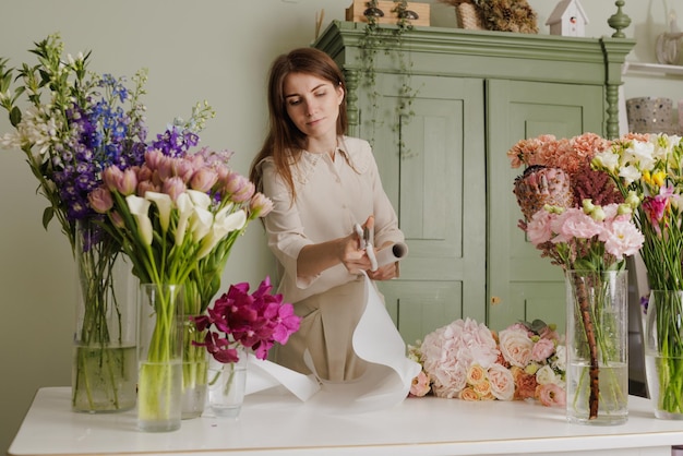 Schönes Mädchen sammelt einen Blumenstrauß in einem Blumenladen