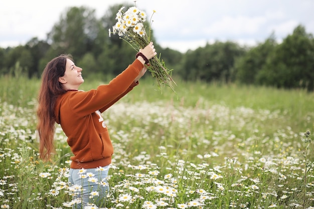 Schönes Mädchen sammelt Gänseblümchen am Sommertag in der Ferne