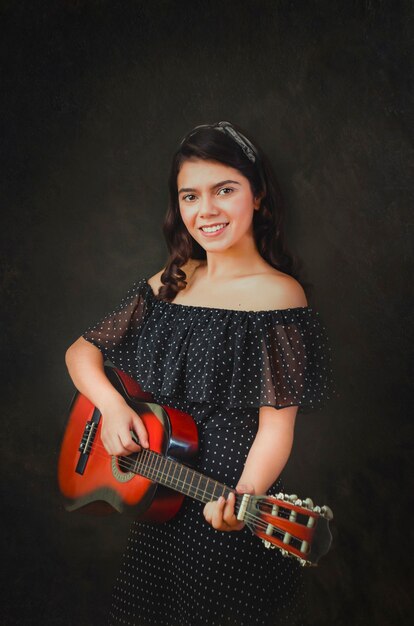 schönes Mädchen spielt Gitarre auf schwarzem Hintergrund