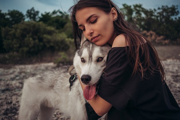 Schönes Mädchen spielt mit einem Hund grau und weiß Husky in den Bergen bei Sonnenuntergang