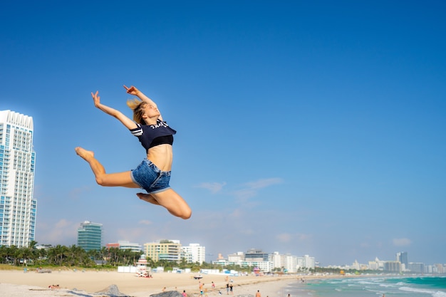 Schönes Mädchen springen mit Südstrand auf Hintergrund, Miami Beach. Florida. Konzept von Glück und Freiheit.