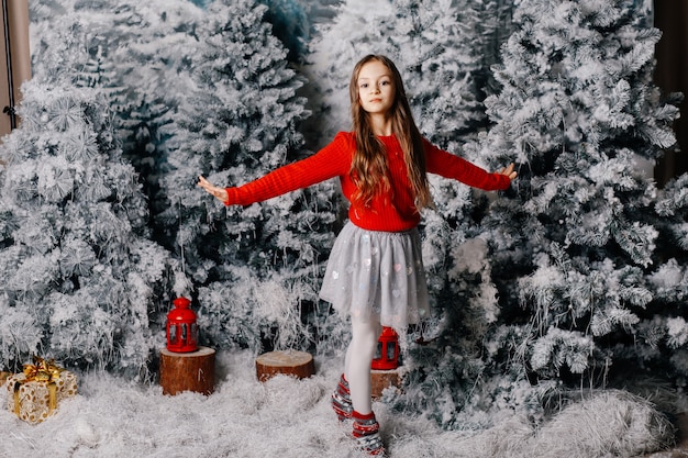 Schönes Mädchen steht auf dem Boden nahe Bäumen der weißen Weihnacht