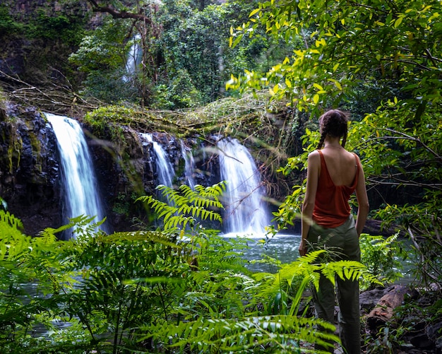 schönes mädchen steht unter einem fabelhaften tropischen wasserfall im australischen regenwald, australien, qld