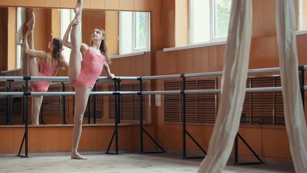 Foto schönes mädchen zeigt erstaunliche flexibilität der beine der ballettstange, zirkusartistin