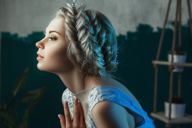 Schönes Modell, das hellblaues Kleid trägt, posiert in einem Studio